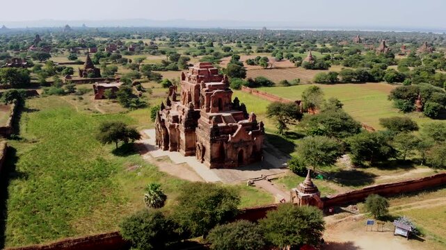 Experience the magnificence of Bagan, Myanmar, where ancient temples rise above lush green fields under a clear blue sky. Journey through time in this enchanting destination.