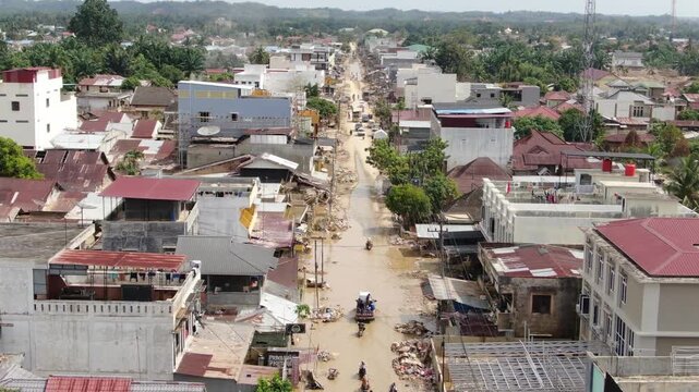 Forward moving drone shot showing straight waterlogged road with cars and motorcycles passing in Aceh Tamiang Indonesia filmed December 2025 after November 2025 flood disaster