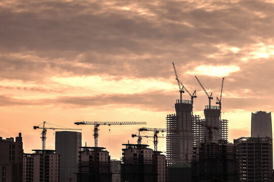 Urban Development Process at Sunset with Construction Cranes