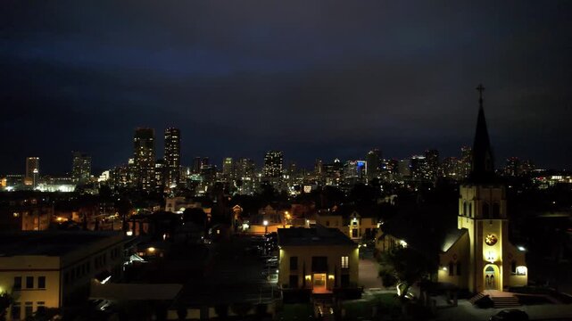 Drone footage flying sideways toward Interstate 94 with the illuminated downtown San Diego skyline and city lights visible at night.