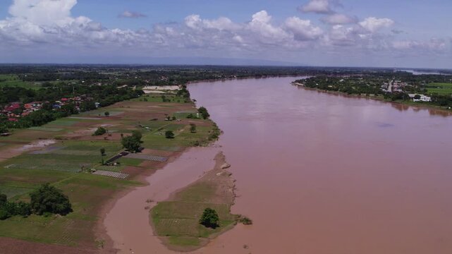 Flying fast high altitude forward moving view of the Mekong River during dry season with Laos and Thailand on the oppositing coastlines.