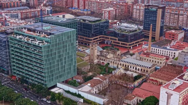 Rooftops, city blocks and streets along Avinguda Diagonal in the Poblenou district of Barcelona, Spain. Aerial drone flyback