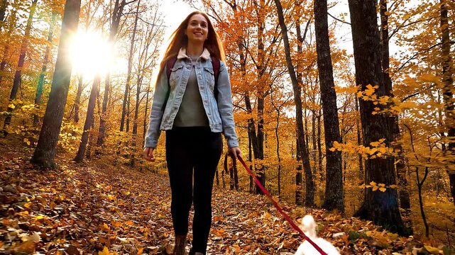 Woman Walking Through Autumn Forest with Dog on a Leash