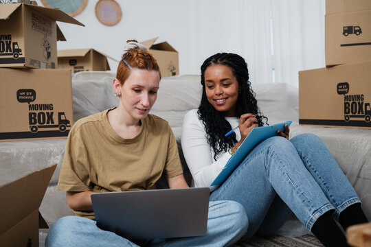 Couple planning move at home with laptop surrounded by moving boxes