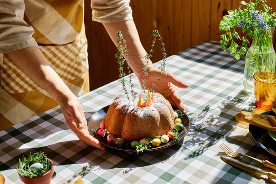 Woman preparing festive homemade bundt cake with easter eggs in rustic kitchen