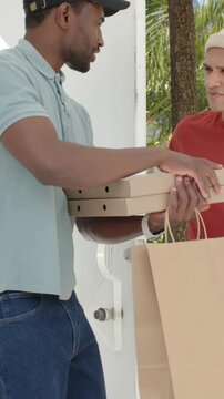 Vertical video: Arriving driver with cap bringing pizza boxes, bag at porch, resident closing door