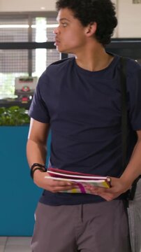 Vertical video: Arriving man holding notes and phone, scanning lobby, pointing to peer with tablet