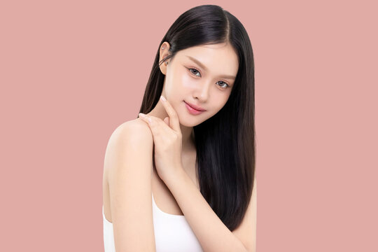 Beautiful young Asian woman with long straight hair and healthy smooth skin isolated on pink background. Ideal for use in beauty skincare commercial campaigns and wellness advertising.