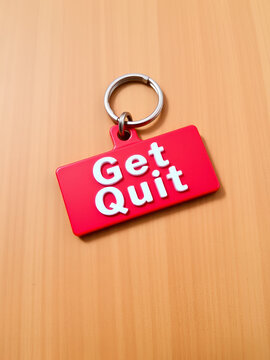 Red keychain with the words 'Get Quit' on a wooden background.