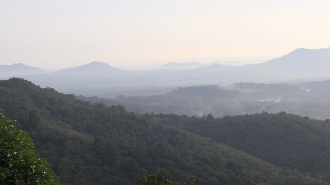 Natural video background of a high-angle atmosphere on a mountain that overlooks the surrounding scenery(mountains, trees,sea)from a scenic vantage point,with a wooden chair for sitting and resting