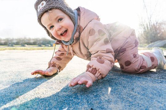 Smiling toddler playing outdoors in winter clothing on sunny day