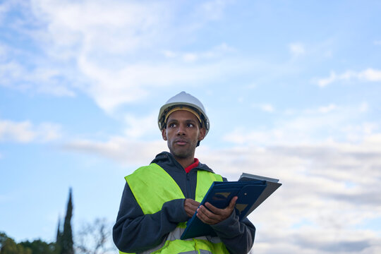 Construction supervisor with helmet and clipboard outdoors