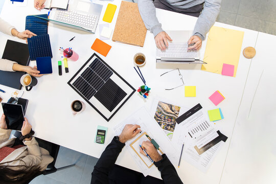 Coworkers collaborating around office meeting table with solar panels