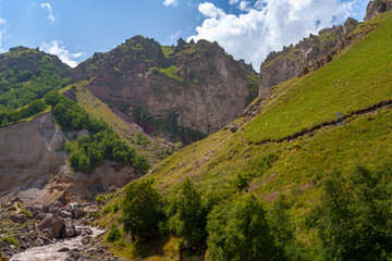 Rocky mountain valley with cave openings, green slopes and hikers. Summer landscape with natural textures, rugged geology, and outdoor travel atmosphere © Tommy