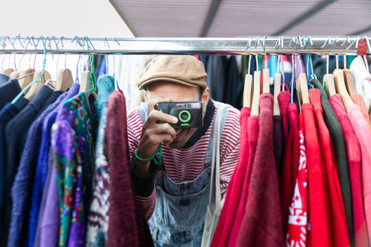 Person taking photo with disposable camera at flea market rack