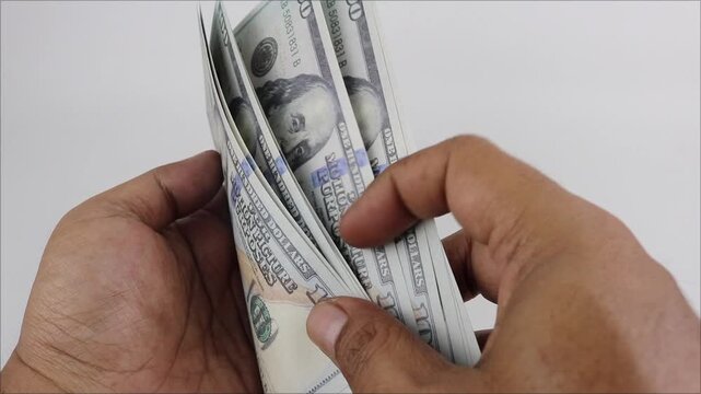 Person counting US dollar banknotes by hand, close-up view, finance management, cash handling activity.