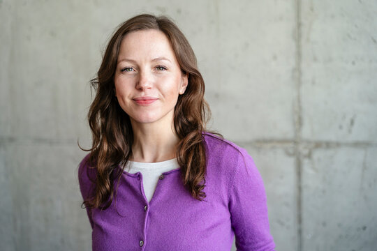 Confident woman in purple sweater at office looking at camera