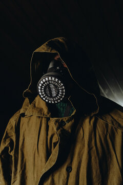 Person in gas mask and raincoat with hood in apocalyptic setting