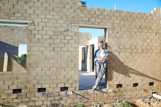 Architect or businesswoman reviewing plans at house construction site