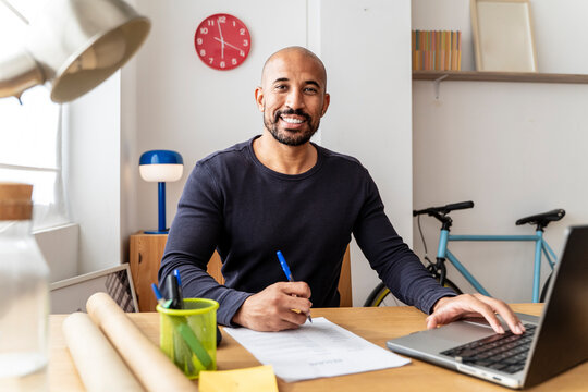 Freelance professional working at home office with laptop and paperwork