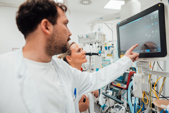Doctors discussing patient data on a monitor in an emergency room