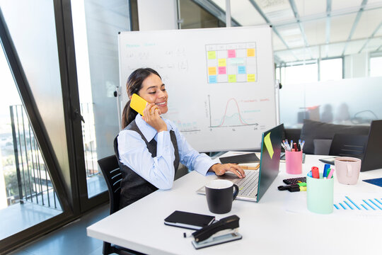 Boss multitasking in modern office talking on phone and working at desk
