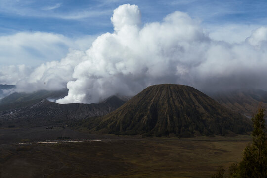 Smoking crater of Mount Bromo volcano in scenic volcanic landscape Java