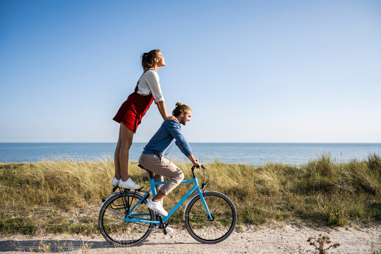 Couple cycling together on beachside path enjoying holiday and freedom
