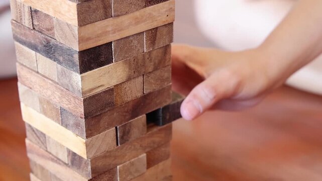 Close Up of Hand Carefully Removing Wooden Block from Tall Tower
