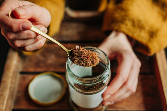 Hand holding spoon with propolis above glass jar of natural remedy