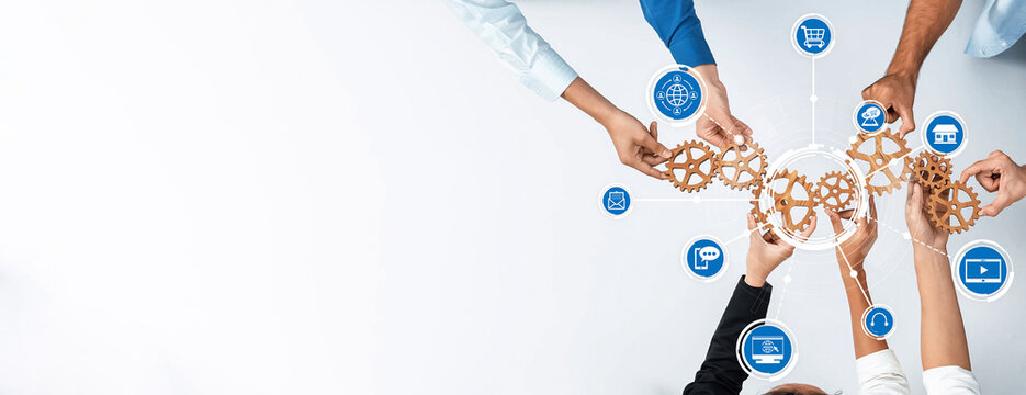 A top-down view of diverse hands working together with gears and technology icons, symbolizing collaboration and innovation in a modern business setting. Amity