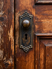 Obraz premium Antique brass doorknob with decorative keyhole on weathered wooden door
