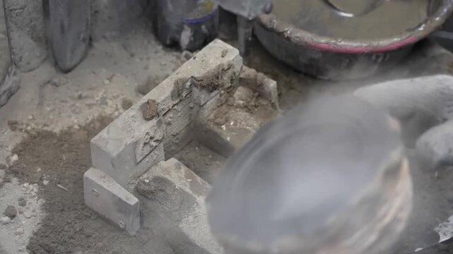Over the shoulder view of a worker inspecting a finished circular graphite mold resting on an industrial workstation