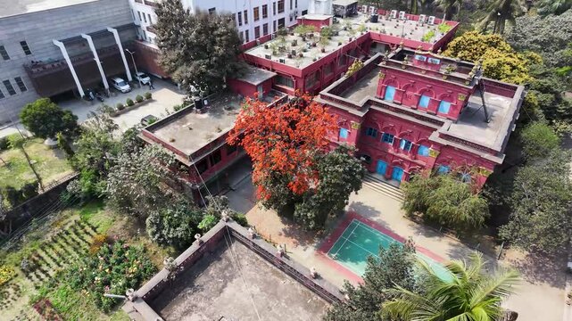 Aerial drone view of modern red brick apartment complex with rooftop gardens and swimming pool in urban residential area