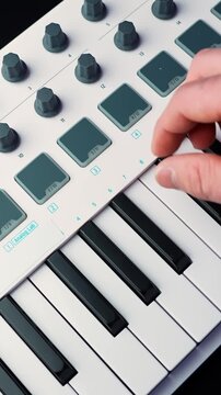Close-up of hand with wedding ring tapping drum pads on a MIDI keyboard controller in a home studio, shallow depth of field for beatmaking and music production b-roll.