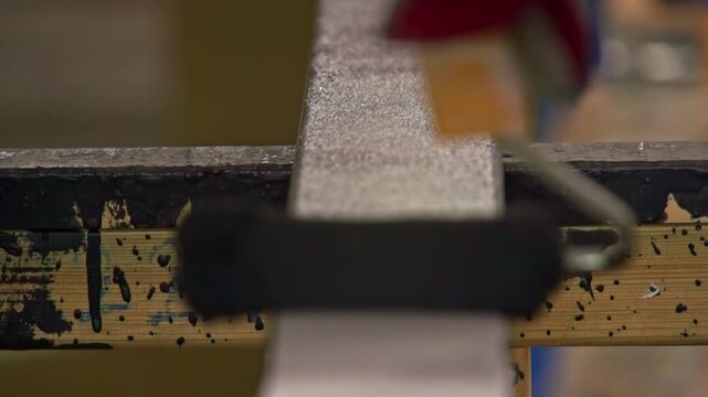 Close up of a worker hand using small roller with black paint on wood