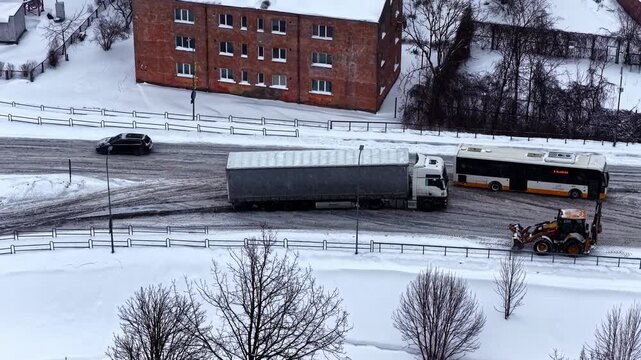 Semi truck navigating icy road in winter, not able to drive uphill and getting stuck, aerial drone hyperlapse