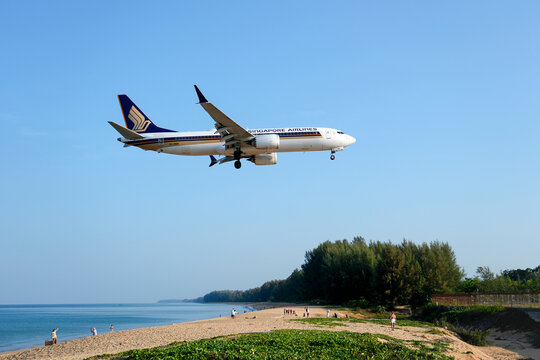 Singapore airlines boeing 737-800 max landing above beautiful beach with people on the beach and sea, travel. Thailand, Phuket International airport. 10 March 2026.