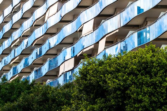 Modern urban architecture captures apartment balcony facade in Benidorm Spain with reflection trees and clean lines showing dense coastal residential life