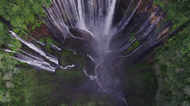 Aerial view of majestic Tumpak Sewu waterfall cascading down lush green cliffs in Indonesia
