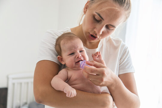 Mother giving pacifier to crying newborn baby, concept of soothing and infant care.