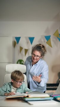 An angry mother tries to explain his homework to her son, making him laugh