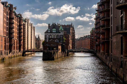 Wasserschloss on canal with brick warehouse architecture in Speicherstadt Hamburg Germany with reflection and clouds captured in strong daylight
