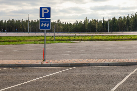A parking sign at a freeway parking lot. The lower sign indicates that parking is parallel to the edge of the roadway, and the stripes indicate the location of the cars
