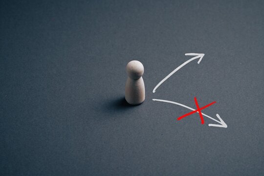 Business decision concept with wooden pawn choosing the right path, wrong choice crossed out with red x arrows showing direction for leadership, career, strategy and decision making