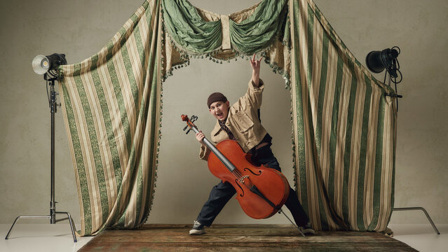 Teen boy playing cello energetically on stage expressive classical music performance. Concept of dynamic music performance, emotional expression through instrument, creative energy, artistic freedom.