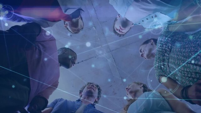 Animation of network of connections over low angle view of diverse colleagues stacking hands