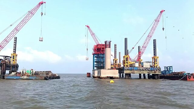 A jack-up platform is installed in the sea for bridge construction, with cranes working on it. They are used to build and shape strong pillars for the bridge foundation.