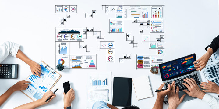 A diverse team collaborates on data analysis and project planning, utilizing laptops and various charts on a modern office table to enhance productivity and communication. Trope