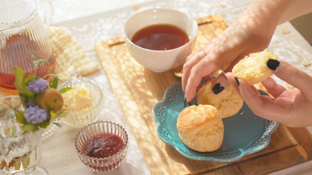 スコーンを割ってクリームやジャムを塗る女性の手元